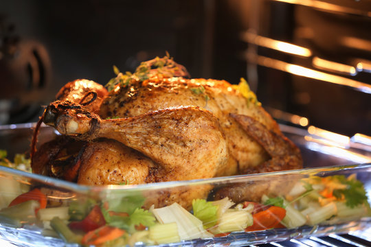 Golden roasted turkey and vegetables on baking dish in oven