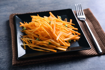 Black square plate with delicious carrot salad on table