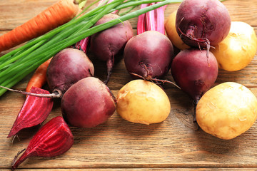 Fresh young beets and potatoes with carrots on table