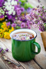 Enameled mug of thyme healing herbs and medicinal herbs bunch on background. Herbal medicine.