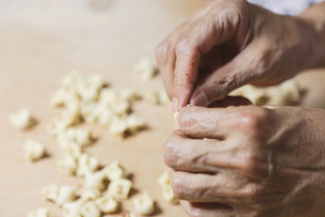 Side view woman's hands make Turkish Ravioli on table. Plates of traditional Turkish food. manti 