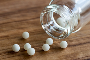 Homeopathic globules and a bottle on a wooden background