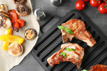 Barbecue grate with tasty grilled steaks on grey table