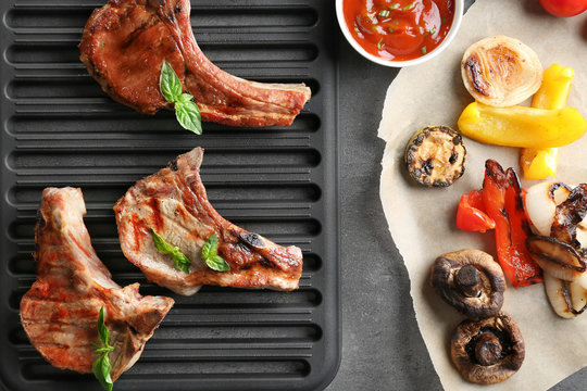 Barbecue grate with tasty grilled steaks on grey table