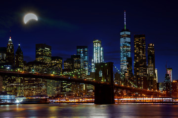 Fototapeta na wymiar Solar eclipse, New York NY august 21 2017 New York City's Brooklyn Bridge and Manhattan skyline illuminated