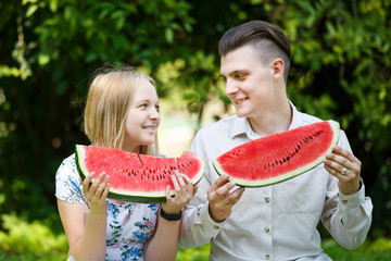 Couple is eating watermelon in a summer park