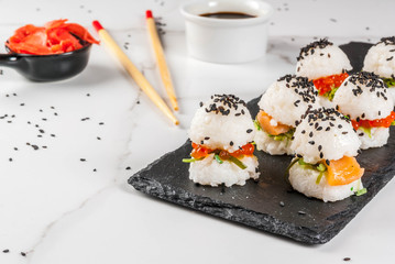 Trend hybrid food. Japanese Asian cuisine. Mini sushi-burgers, sandwiches with salmon, hayashi wakame, daikon, ginger, red caviar. White marble table, with chopsticks, soy sauce. Copy space