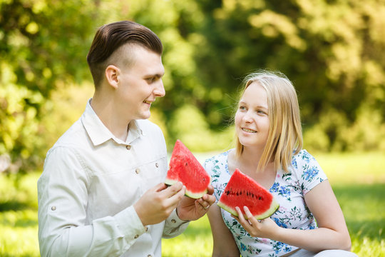 Couple is eating watermelon in a summer park
