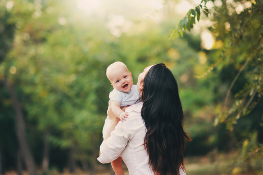 Молодая мама играет со своим маленьким сыном на поляне