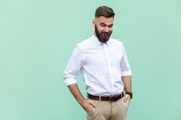 Obraz premium Cunning businessman, hid his hands in his pockets and looking slyly at camera. Indoor, studio shot