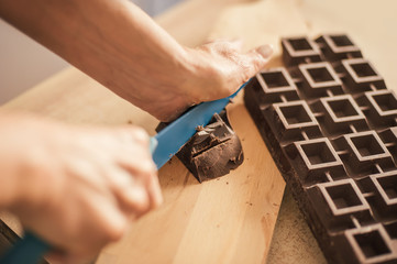 Woman hands chopping chocolate block for celebratory cake