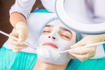 Naklejka premium Happy relaxed man in cosmetology clinic. Time to care skin. Professional Cosmetic services using