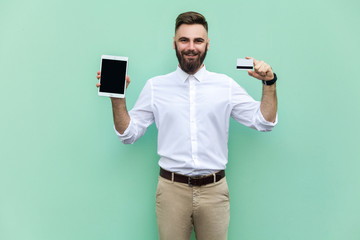 Online shopping or banking. Young adult businessman holding hands credit card and tablet and...