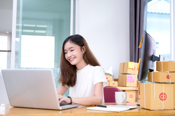 Young asian girl freelancer business private working at home office with laptop, note, coffee, packaging delivery online market on purchase orders to customer.