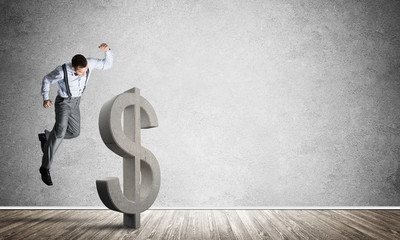 Determined banker man in empty concrete room breaking dollar figure