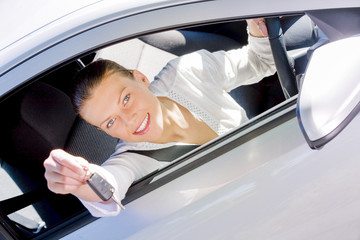 Young pretty woman in casual clothes driving a car, showing her car keys