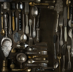 Cutlery, forks, spoons, and knives on dark wooden background