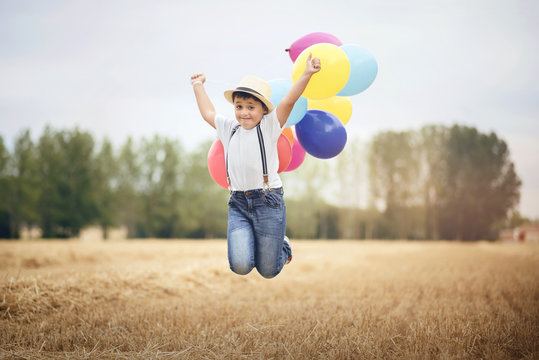 niño saltando con globos en el campo