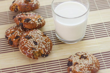 Biscuits on the table with sesame seeds, raisins and a glass of milk