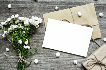 blank white greeting card with white flowers bouquet and envelope with gift box and buds