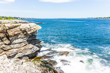 Cliff rocks side view by Portland Head Lighthouse in Fort Williams park in Cape Elizabeth, Maine during summer day