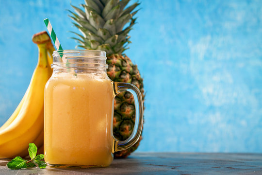Smoothies of pineapple, banana and orange in a glass jar. Freshly prepared drink with space for text