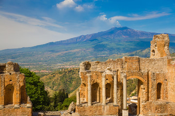 Fototapeta premium Panoramic view of beautiful town of Taormina with its greek amphitheatre and Etna volcano background, Sicily island, Italy