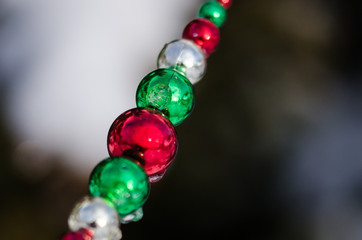 Red, Green and Silver Christmas Ornament Beads Decorating a Snowy Outdoor Tree