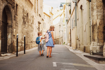 Group of two kids walking on the streets of old european town, wearing backpacks. Travel with...