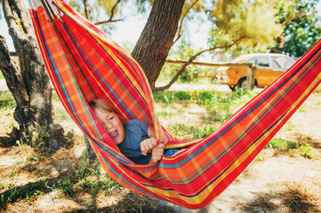 Funny little boy playing in hammock, child resting in garden