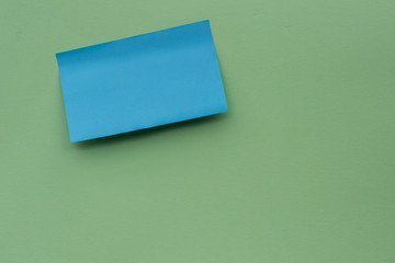 Post note paper sheet or sticky sticker with sadow on green background. Blue post office memo or remember notepaper. Empty space for text.