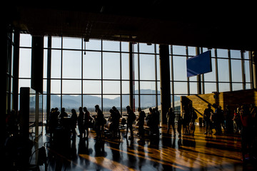 Silhouette crowd people waiting for airplane in airport terminal with mountain background