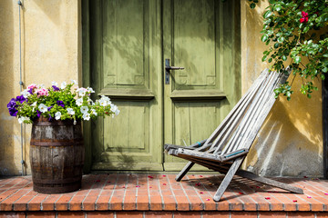 Old fashioned porch decorated with wooden chair and bucket with flowers