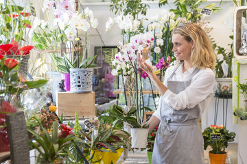 Young florist with an orchid in her shop