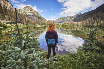 Naklejka premium a young woman hiking next to a mountain lake