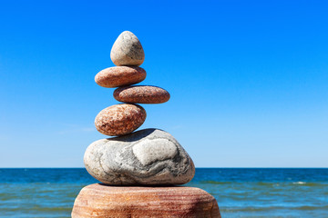 Stones balance on a background of blue sky and sea