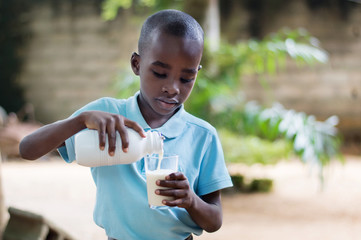 Child pouring milk into a glass.
