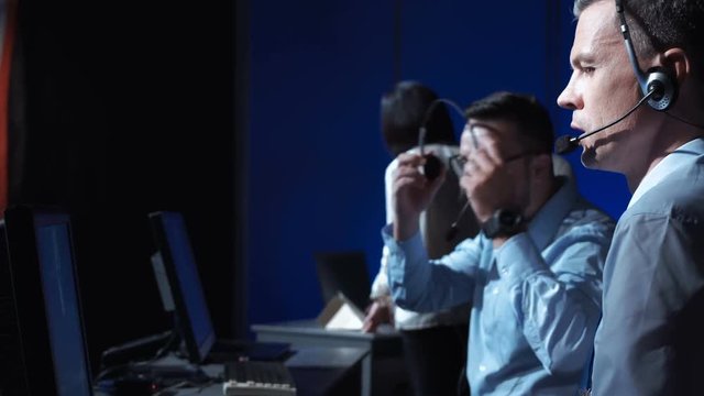 Side view of supervisor man in headset sitting and working in space mission control center. Watching flight of satellite. Elements of this image furnished by NASA.