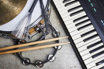 a group of musical instruments including a keyboard, drum, and tambourine.