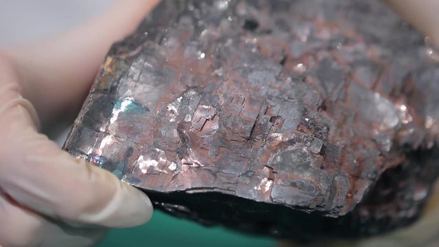 Female hands in white gloves holding stone mineral. Stone macro, gray rough stone. Fluorite mineral stone, fluorite mineral stone. Scientist studying the stone material close up