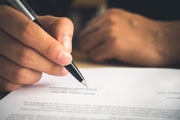 hand of businessman writing on contract/book/notebook, signing a signature for business agreement.