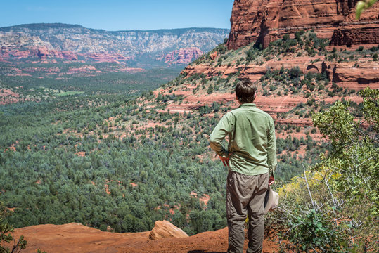 Arizona view over valley near Sedona, with red rock mountains and solitary man standing and looking over the valley.