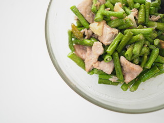Thai local stir fried green long string bean and pork meat, in glass bowl, with white background