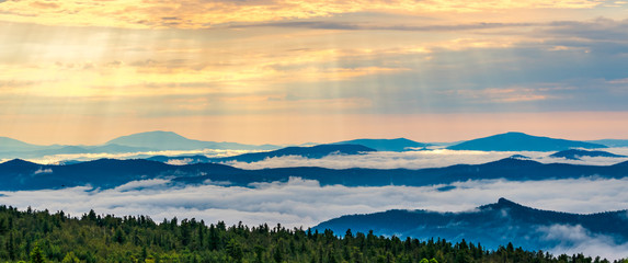 Morning mist over the tops of mountains and woods at spectacular sunrise