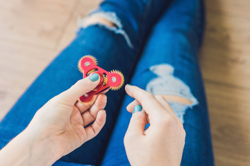 Girl teenager in holey jeans holds in hands and plays with spinner