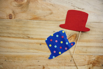 Top or flat lay view of Photo booth props a red hat and a blue polkadot hat on a wooden background flat lay. Birthday parties and weddings.