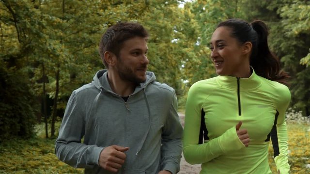 Tracking slow-motion of man and woman communicating and smiling during morning jog.Rapidly slomo phantom flex front shot