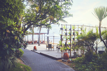 Cafe and restaurant chairs with table and umbrella at beach. Famous travel destination in Sanur, Bali, Indonesia.
