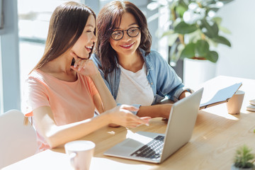Joyful delighted friends looking at the laptop screen