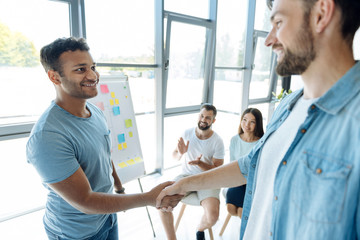 Obraz premium Delighted positive men shaking hands